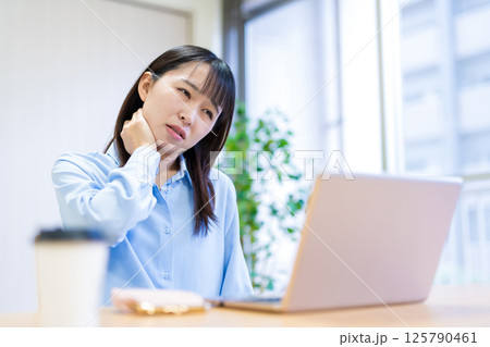 テレワーク疲れの女性 肩こり 首の痛み リビングでテレワークをする若い女性 テレワーク疲れの女性 肩こり 首の痛み リビングでテレワークをする若い女性 125790461