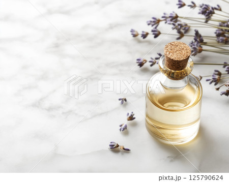 Small glass bottle with lavender oil and scattered flowers Small glass bottle with lavender oil and scattered flowers 125790624