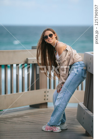 Beautiful adorable girl outdoors in the park with ocean view Beautiful adorable girl outdoors in the park with ocean view 125790937