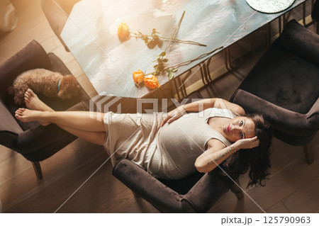 Beautiful pregnant woman at home sitting at the table Beautiful pregnant woman at home sitting at the table 125790963