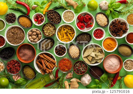 A colorful assortment of fresh, fragrant spices and herbs displayed on a soft green background, capturing a vibrant culinary essence A colorful assortment of fresh, fragrant spices and herbs displayed on a soft green background, capturing a vibrant culinary essence 125791016