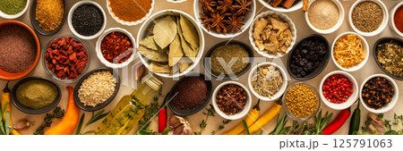 Collection of assorted spices and herbs spread on a beige background, blending exotic aromas and colors to inspire flavorful cooking, banner 125791063
