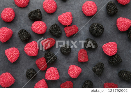 Red chewing sweets in the form of berries. Sweets in the form of raspberries on dark background. Space for text Red chewing sweets in the form of berries. Sweets in the form of raspberries on dark background. Space for text 125792002