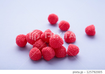 Red chewing sweets in the form of berries. Sweets in the form of raspberries on purple background. Space for text Red chewing sweets in the form of berries. Sweets in the form of raspberries on purple background. Space for text 125792005