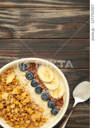 Oat raisin granola with fresh summer berries in a bowl on brown wooden background. Concept of healthy breakfast food, clean eating, dieting 125792007
