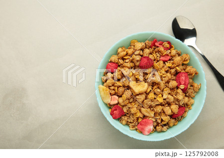 Granola with strawberries in a bowl on light background. 125792008