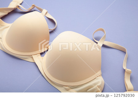 Beige female bra on purple background. Compression bra for breast. Top view 125792030