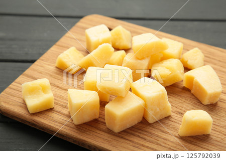 Cheese cubes on cutting board on black background. Parmesan 125792039