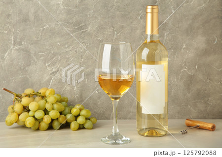 Bottle and glass with white wine with grape on grey background. Bottle and glass with white wine with grape on grey background. 125792088