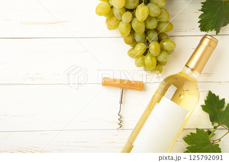 Bottle white wine with grape on white wooden background. Bottle white wine with grape on white wooden background. 125792091
