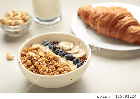 Beautiful morning breakfast with fresh croissants, granola with yoghurt and berries and fruit on plate. Tasty and healthy breakfast on white wooden table Beautiful morning breakfast with fresh croissants, granola with yoghurt and berries and fruit on plate. Tasty and healthy breakfast on white wooden table 125792224