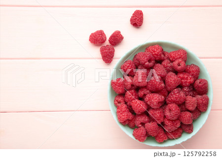 Raspberries in mint bowl on pink background. Space for text 125792258