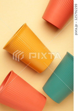 Eco plastic glass of various color on beige background. Space for text. Vertical Eco plastic glass of various color on beige background. Space for text. Vertical 125792299