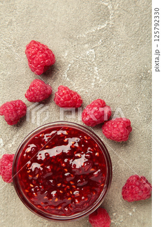 Raspberry jam jelly in bowl with berries on grey concrete background. Raspberry jam jelly in bowl with berries on grey concrete background. 125792330