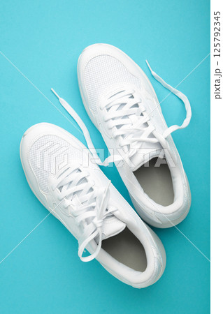 White sneakers on a blue background. Vertical photo 125792345