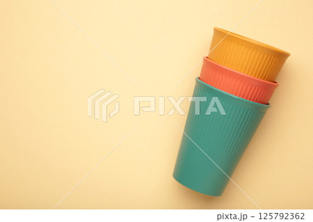 Eco plastic glass of various color on beige background 125792362