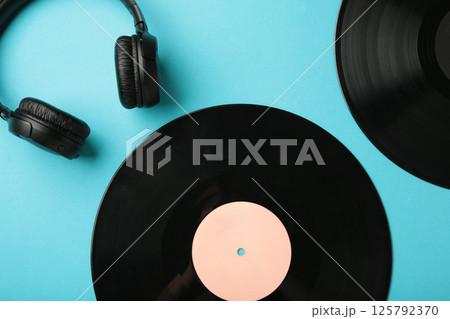 Retro vinyl record with headphones on blue background. Retro style. Flat lay. 125792370