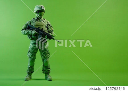 A soldier wearing camouflage uniform and helmet stands confidently holding a rifle. The bright green background creates a striking contrast, emphasizing the soldiers readiness and focus. A soldier wearing camouflage uniform and helmet stands confidently holding a rifle. The bright green background creates a striking contrast, emphasizing the soldiers readiness and focus. 125792546