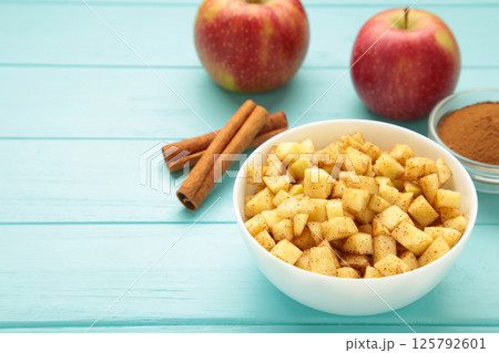 Apples with cinnamon on plate on blue background. Red apples with cinnamon sticks and star anise. Apples with cinnamon on plate on blue background. Red apples with cinnamon sticks and star anise. 125792601