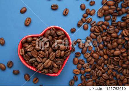 Coffee beans in the heart shaped bowl on blue background. Top view 125792610