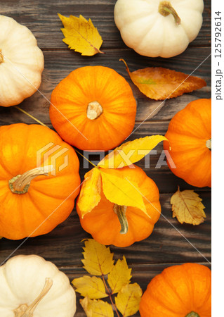 Autumn composition. Fresh orange and white pumpkin with autumn leaves on brown wooden background. Top view 125792614