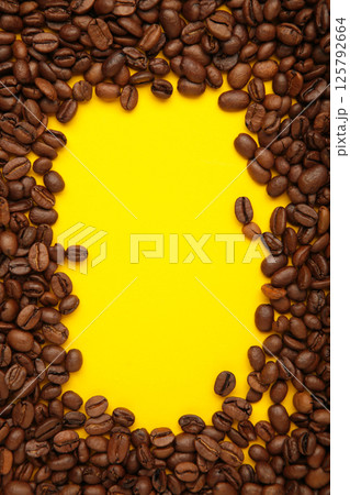 Black coffee beans on yellow background. Space for text 125792664