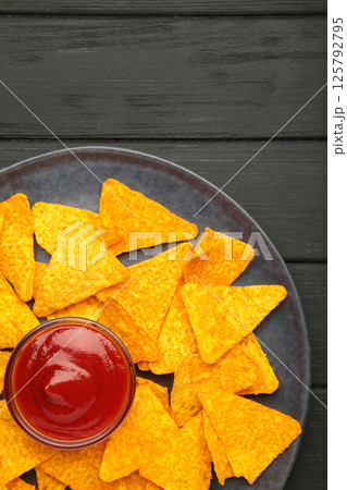Nachos and ketchup on plate on black background. Mexican dish. Top view 125792795