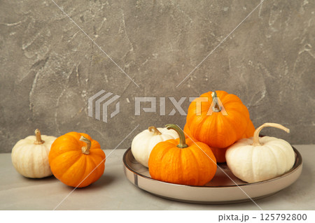 Autumn composition. Fresh orange and white pumpkin on plate on grey background. Top view Autumn composition. Fresh orange and white pumpkin on plate on grey background. Top view 125792800