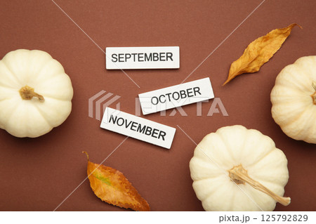 Welcoming autumn spirit. Calendar with September, October, November month with pumpkin on brown background. Top view 125792829