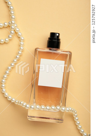 Pearl necklace with glass perfume bottle unlabeled displayed. Minimal concept for advertising with mockup for design. 125792927