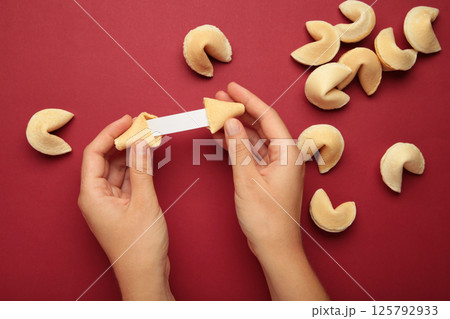 Woman holding tasty fortune cookie and paper with prediction on red background. Space for text 125792933