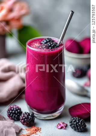 Vibrant blackberry and beet smoothie in a glass with metal straw and fresh berries on gray background. 125793507