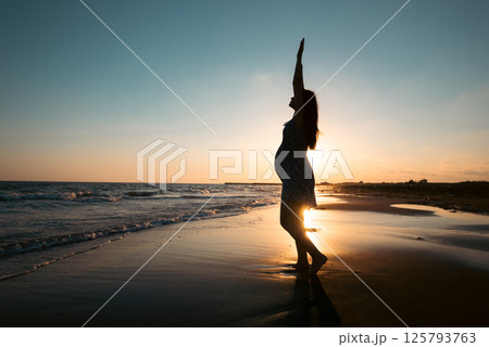 Silhouette of pregnant woman on the beach against sunset. 125793763