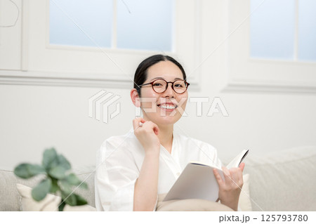 ソファ読書をするウィルビー女性｜勉強｜趣味｜健康的な暮らしイメージ｜ウェルビー女子｜ウェルビーイング 125793780