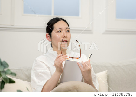 ソファ読書をするウィルビー女性｜勉強｜趣味｜健康的な暮らしイメージ｜ウェルビー女子｜ウェルビーイング 125793786