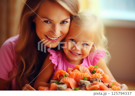 Mother and daughter posing with a variety of delicious sushi rolls in a trendy sushi bar 125794337