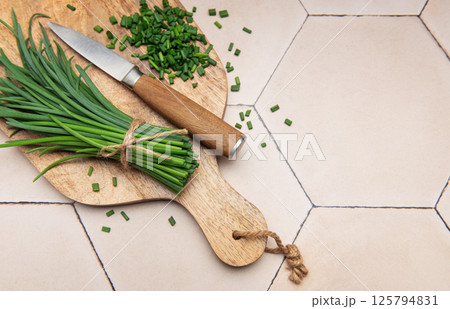 Fresh chopped chives on wooden cutting board 125794831
