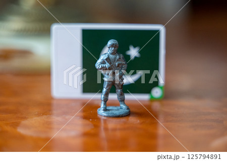 A tin soldier on the background of the flag of Pakistan. India Pakistan military conflict 125794891