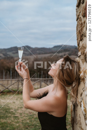 Woman Toasts with Champagne Glass in Scenic Vineyard Woman Toasts with Champagne Glass in Scenic Vineyard 125796019