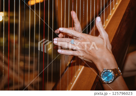 Close-Up of Hands Playing a Harp with Precision Close-Up of Hands Playing a Harp with Precision 125796023
