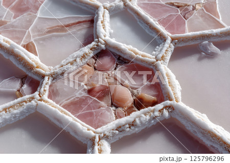 Close up of crystallized salt formations on pink surface, showcasing intricate geometric patterns and textures. image highlights natural beauty and complexity of mineral deposits 125796296
