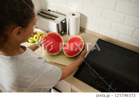 Woman Preparing Fresh Watermelon in a Modern Kitchen 125796373
