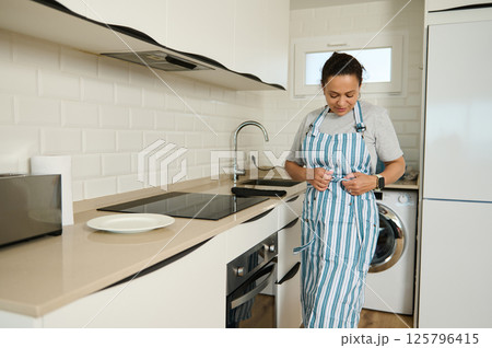 Woman Preparing for Cooking in a Modern Kitchen Woman Preparing for Cooking in a Modern Kitchen 125796415
