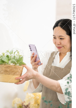 室内で植物を撮影するミドル女性｜花屋園芸店教室イメージ｜ウェルビー女子｜ウェルビーイング 125796921