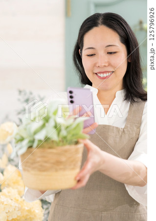 室内で植物を撮影するミドル女性|花屋園芸店教室イメージ|ウェルビー女子|ウェルビーイング 室内で植物を撮影するミドル女性|花屋園芸店教室イメージ|ウェルビー女子|ウェルビーイング 125796926