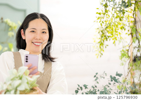 室内で植物を撮影するミドル女性｜花屋園芸店教室イメージ｜ウェルビー女子｜ウェルビーイング 125796930