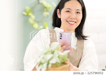 室内で植物を撮影するミドル女性｜花屋園芸店教室イメージ｜ウェルビー女子｜ウェルビーイング 125796932