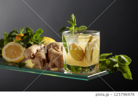 Ginger cocktail with lemon and mint in a frozen glass on a black background. Ginger cocktail with lemon and mint in a frozen glass on a black background. 125796976