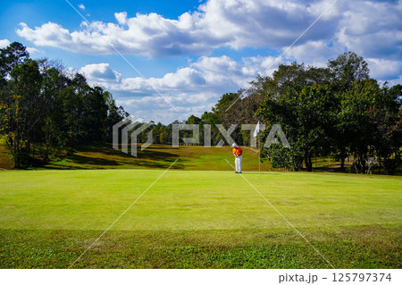 Golfer playing golf in the evening golf course, on sun set evening time. Golfer playing golf in the evening golf course, on sun set evening time. 125797374