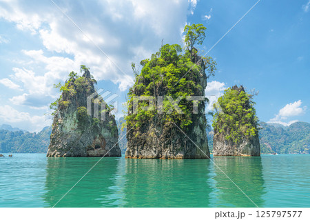 A panorama of famous natural places in Thailand - Three rocks, like three brothers, in the middle of turquoise water on the emerald Cheo Lan Lake in Khao Sok Park. The business card of tourism and 125797577